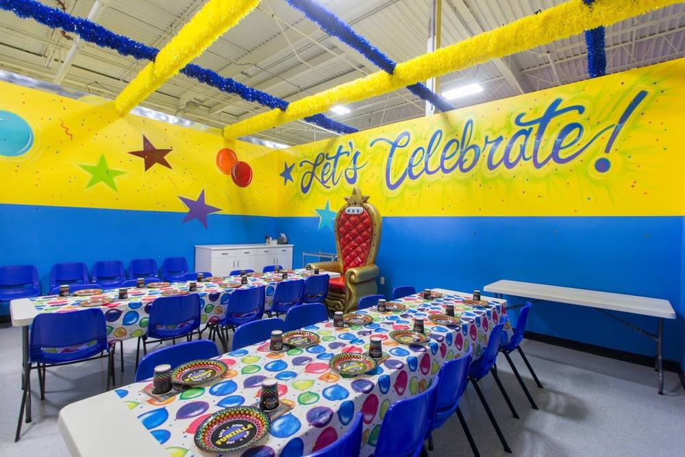 Funzilla party room set for a celebration with a throne chair and a “Let’s Celebrate!” mural